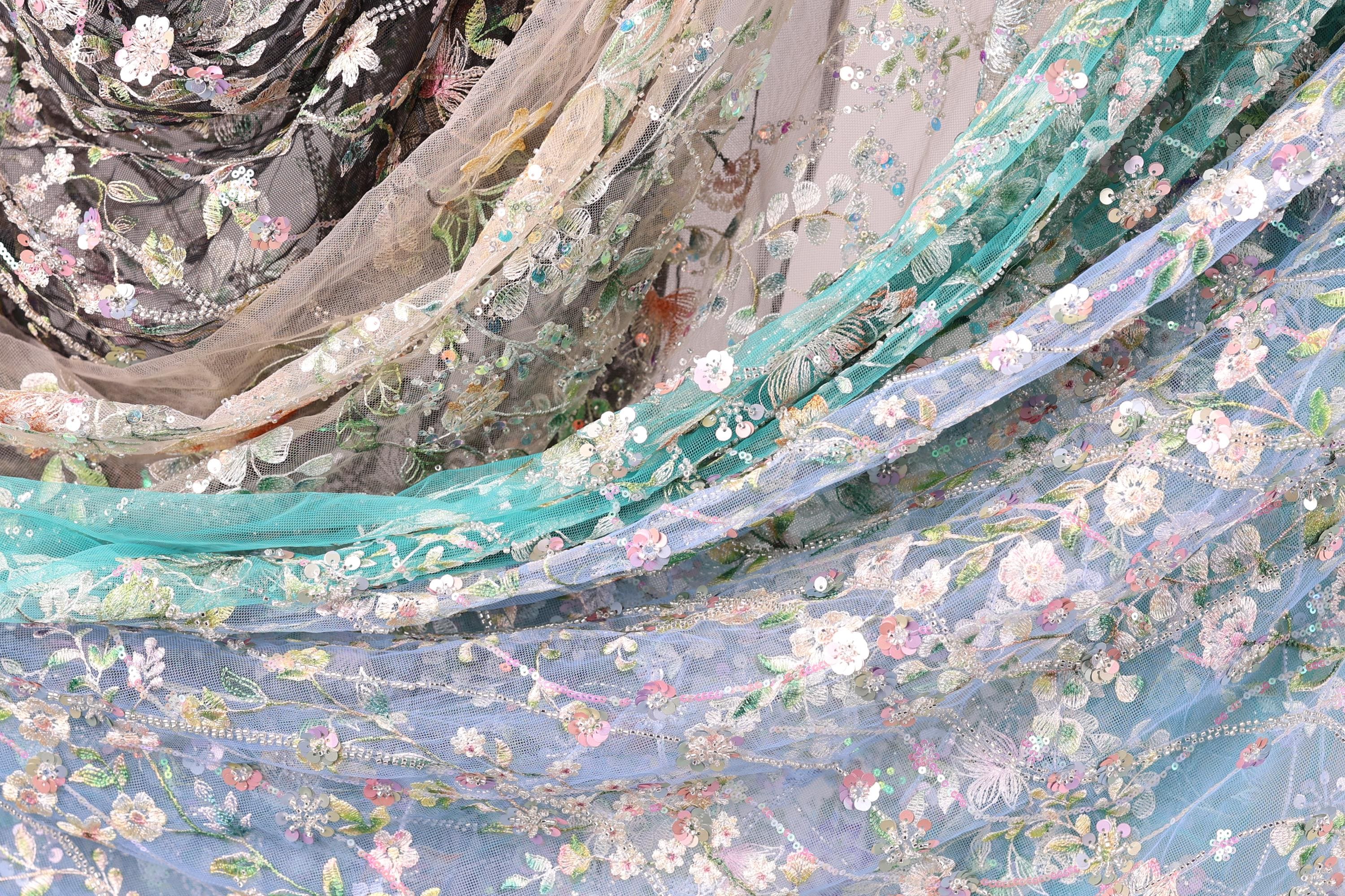 The image is a close-up of a fabric with a floral pattern, featuring various shades of blue, green, and white.