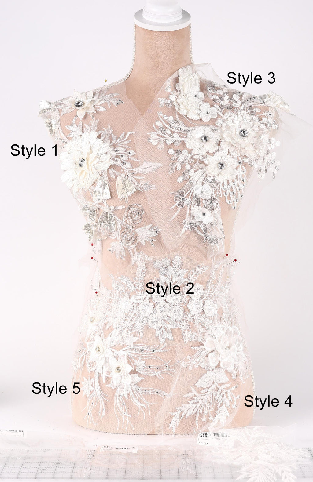 A mannequin with a white lace bodice adorned with various floral and leaf-like embellishments, each labeled with a different style number.