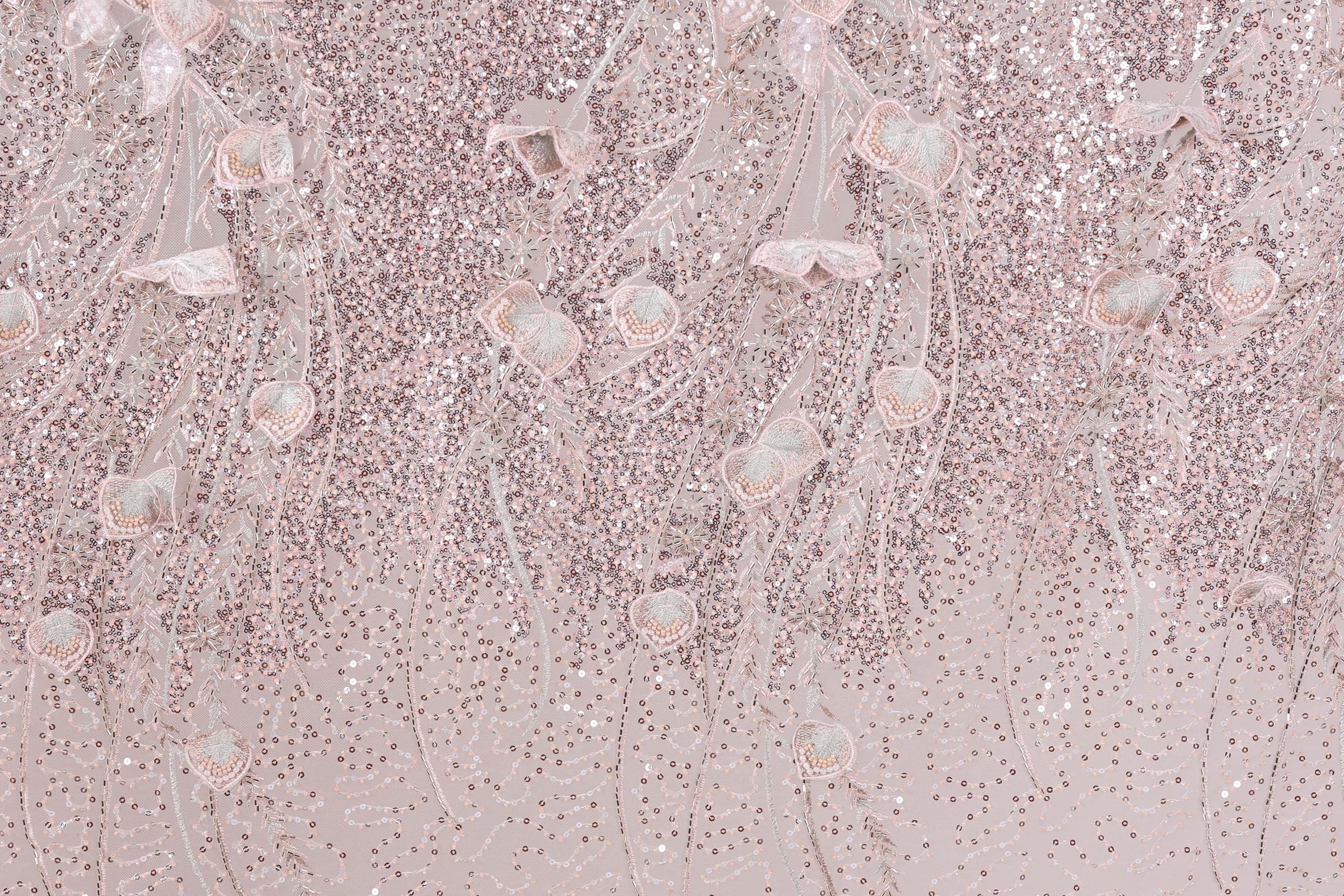 a background with a pink and white color scheme, adorned with a pattern of sequins and delicate flowers. The pattern appears to be a decorative textile or fabric, with the pink and white colors creating a visually appealing and harmonious design.