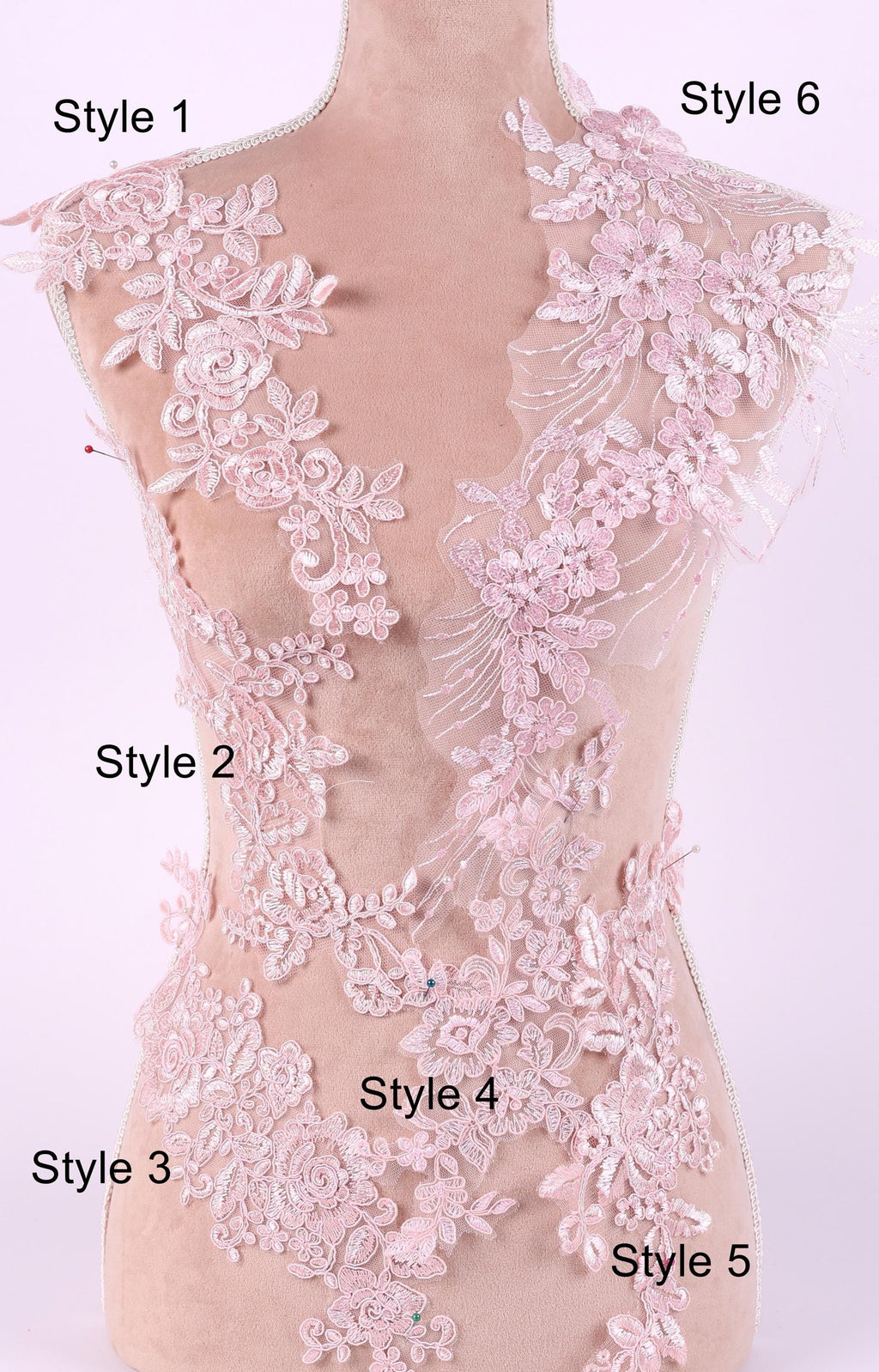 A mannequin with a pink lace bodice and various lace patterns and designs, including floral, leaf, and feather motifs, displayed on it.