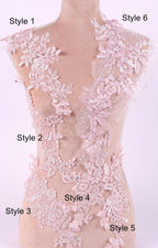 A mannequin with a pink lace bodice and various lace patterns and designs, including floral, leaf, and feather motifs, displayed on it.