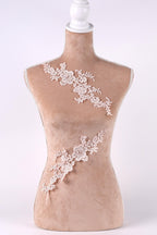 A mannequin with a beige body and a white headpiece, both adorned with delicate white lace or floral embroidery.
