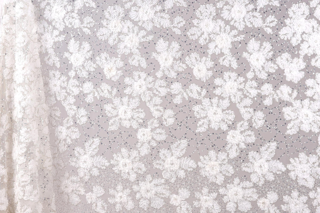 a close-up view of a delicate, white lace fabric with a floral pattern. The fabric appears to be made of sheer material, giving it a delicate and elegant appearance. The lace fabric is spread across the entire image, creating a sense of depth and texture. The floral pattern on the fabric is intricate and detailed, showcasing the craftsmanship and artistry involved in creating such a piece of textile art.