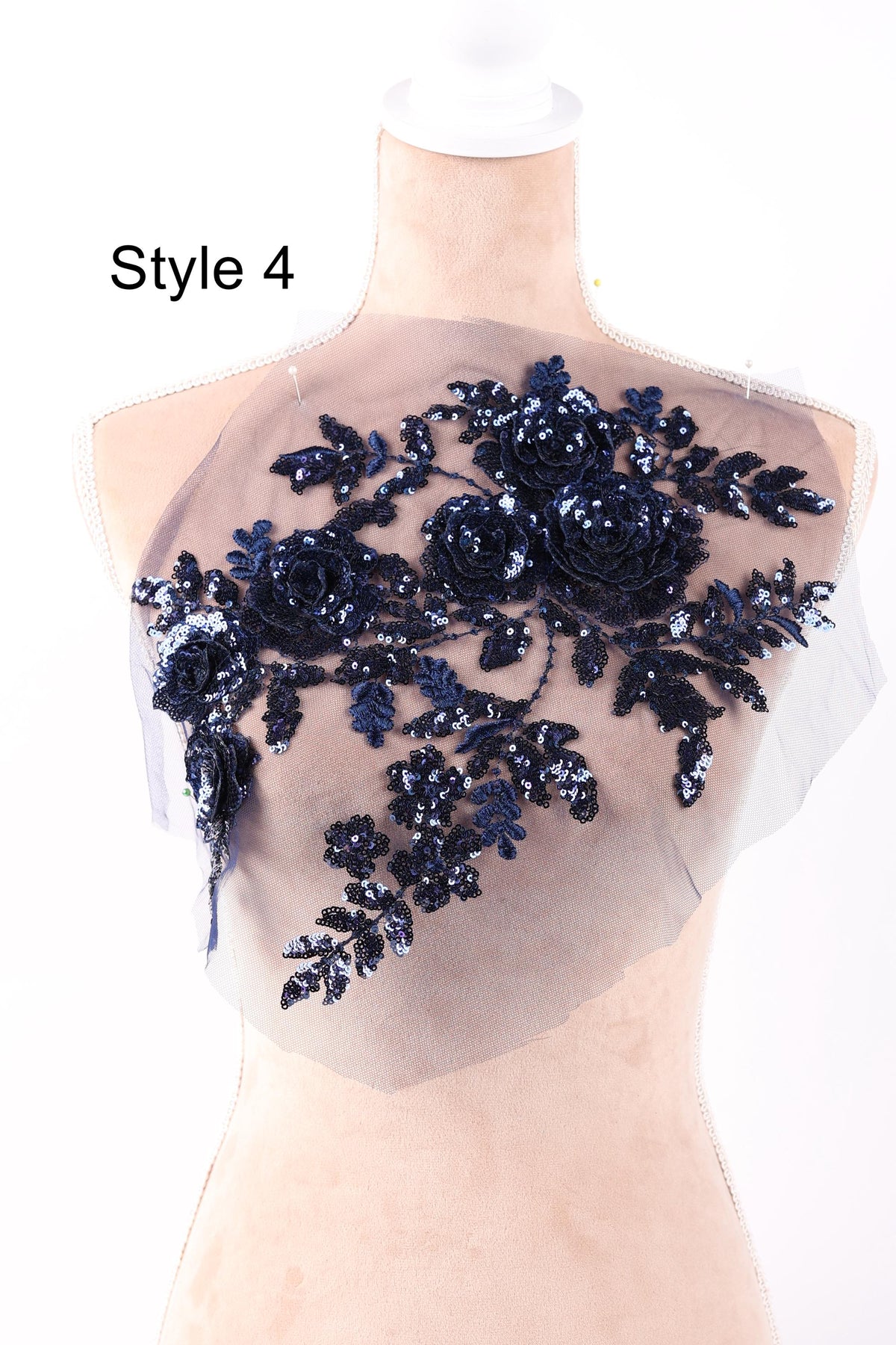 A mannequin wearing a dress with a floral pattern made of sequins and lace.