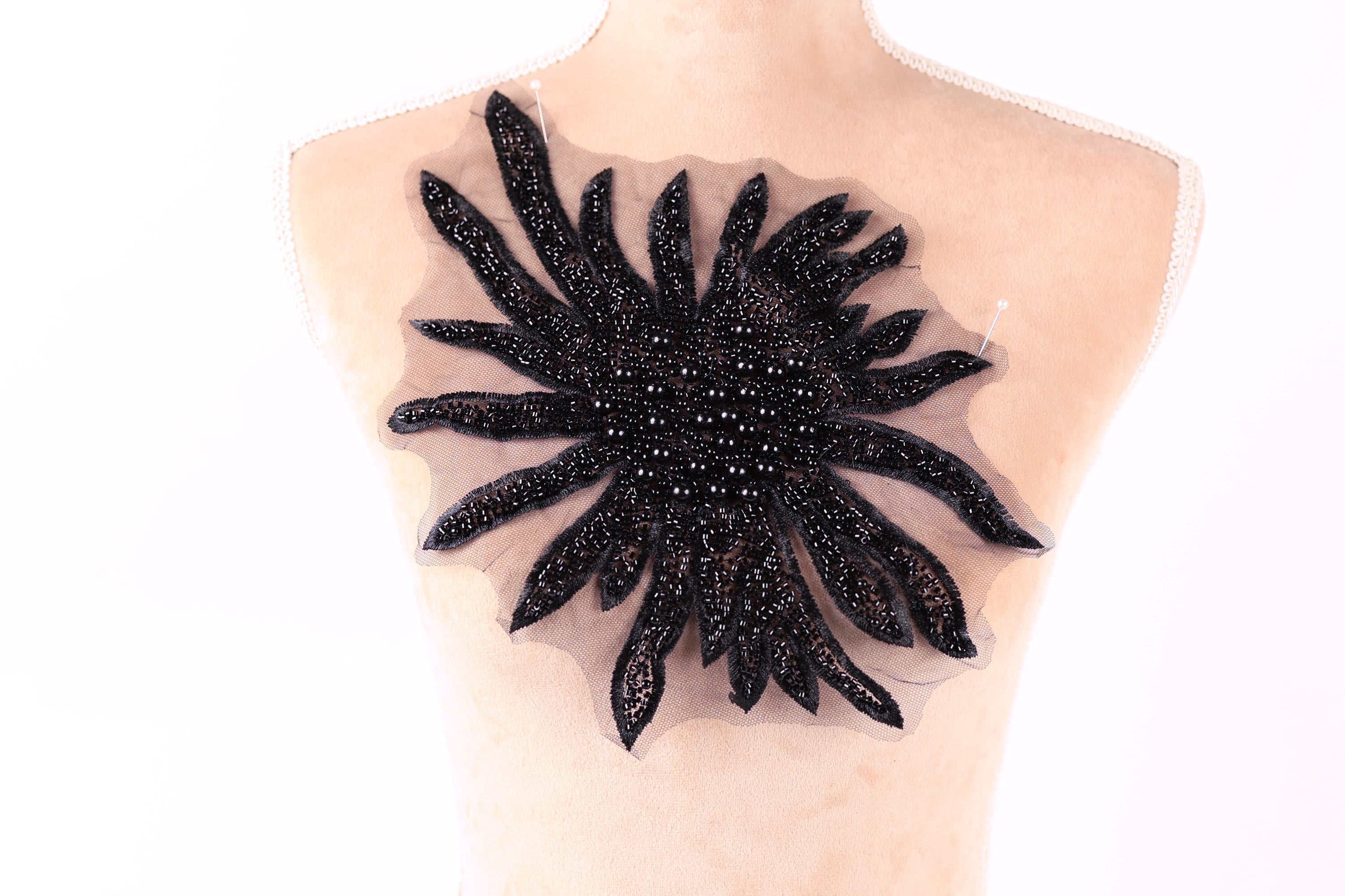 a mannequin with a large, black, beaded flower-shaped embellishment on its bust.
