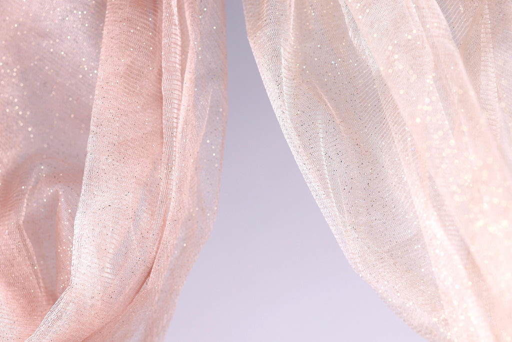two pieces of fabric, one in a soft pink color and the other in a lighter shade of pink, with a subtle glittery texture.