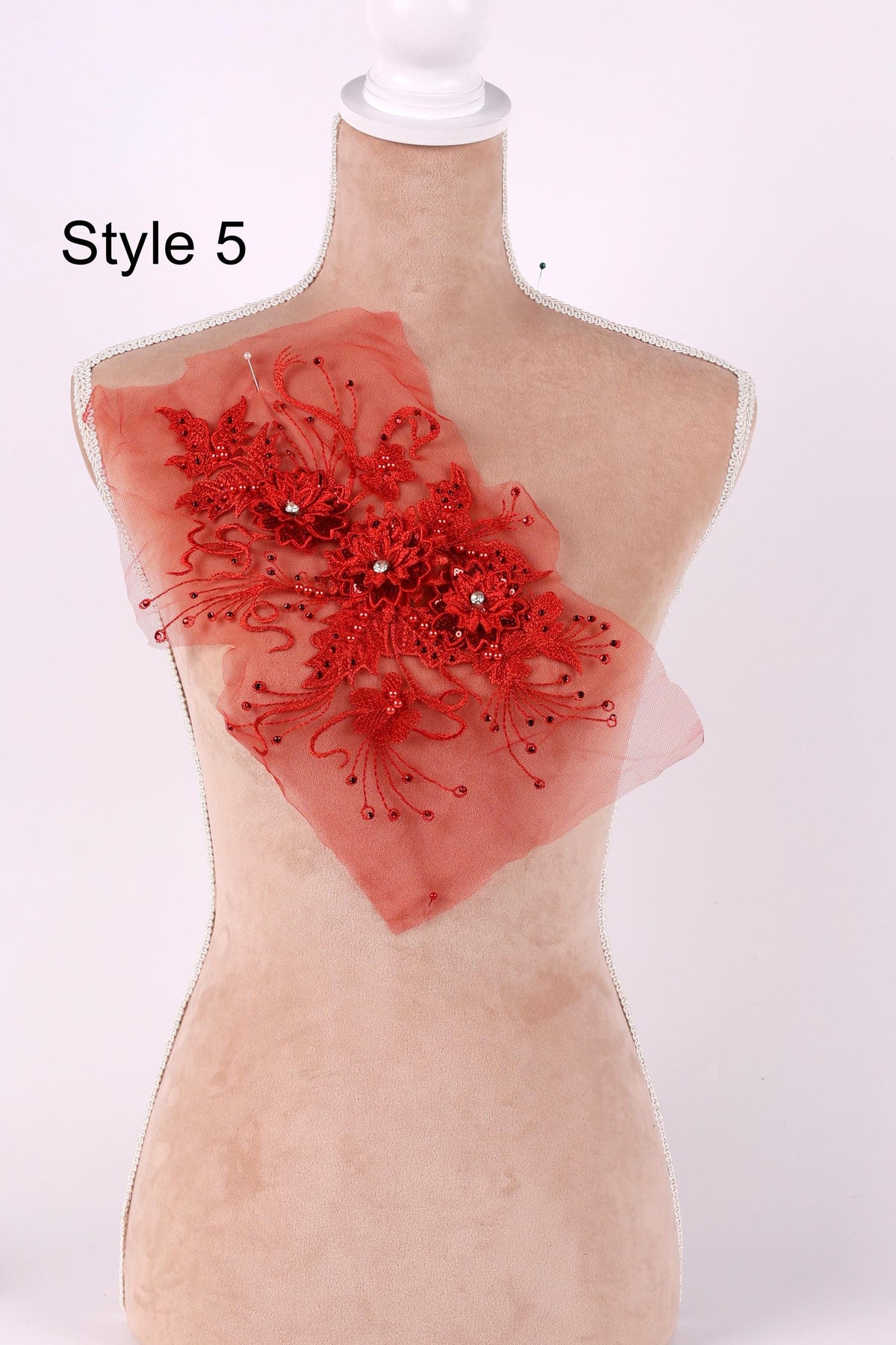 A mannequin with a red floral embellishment on its chest.