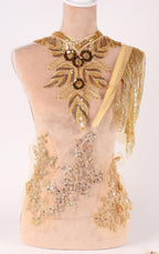 A mannequin wearing an elaborate gold and beige dress with intricate embroidery and embellishments.