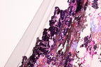 a close-up view of a fabric with a vibrant purple and pink sequin pattern. The fabric appears to be a sheer material, with a mix of purple and pink sequins that create a visually striking and intricate design.