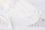 a close-up view of a white fabric, possibly a piece of clothing or a textile, with a ruler visible in the background.