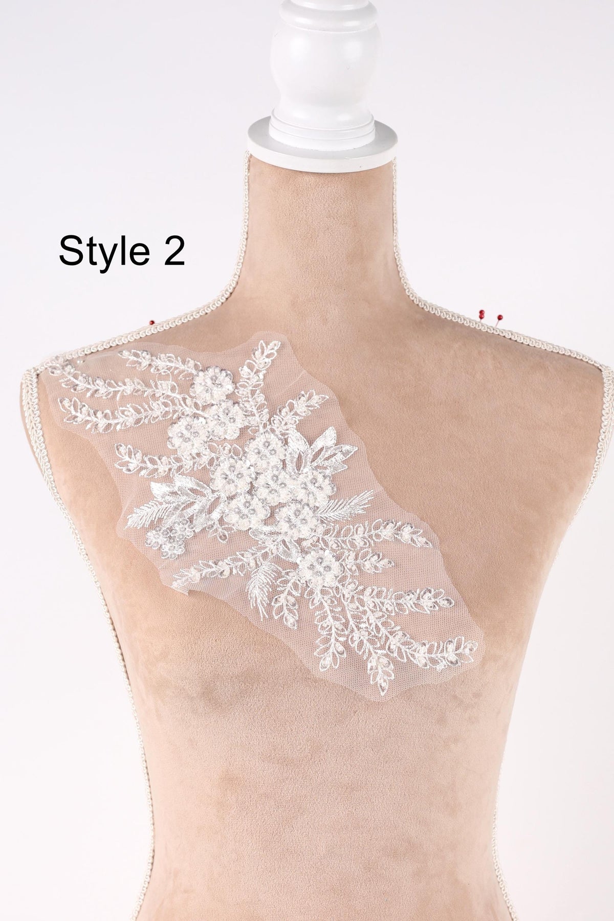 A mannequin with a white lace overlay on its bust, displaying a floral pattern.