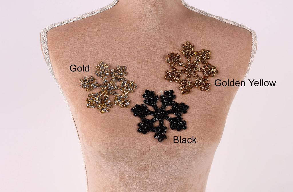 A mannequin torso with three different colored snowflake-shaped embellishments on it, labeled as gold, golden yellow, and black.