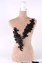 A mannequin with a beige body and black lace or sequin embellishments on its chest area.