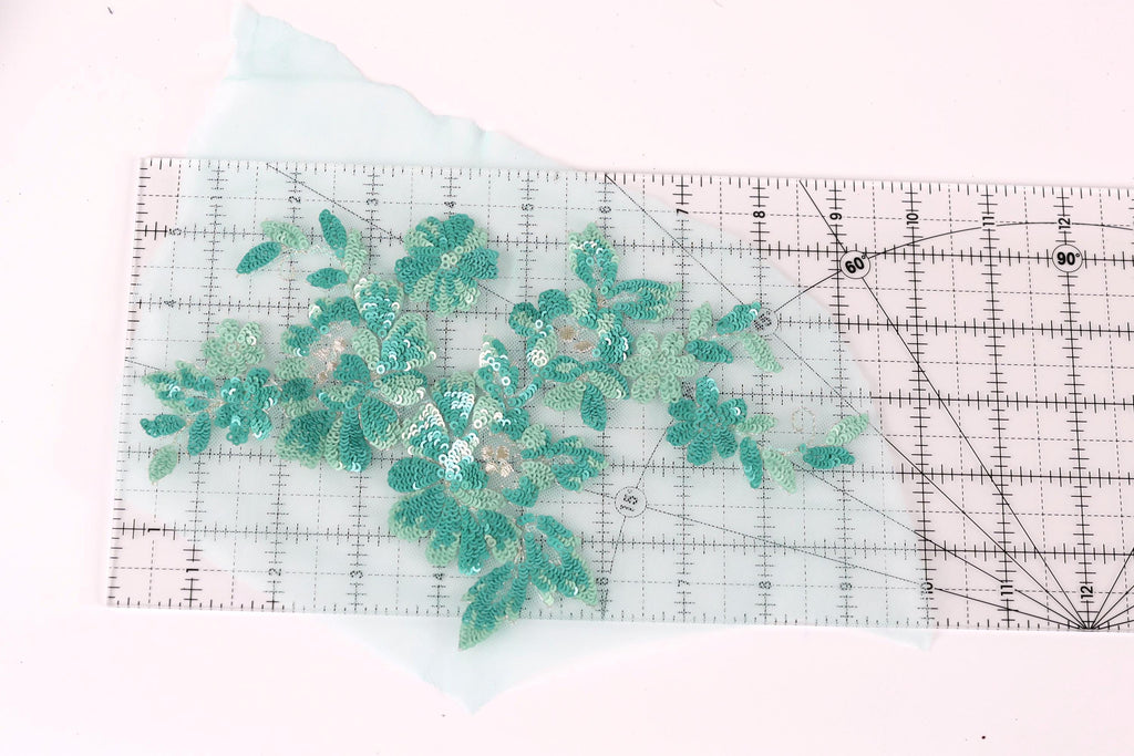 a clear ruler with a floral pattern of green sequins and leaves on it.