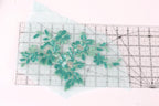 a clear ruler with a floral pattern of green sequins and leaves on it.