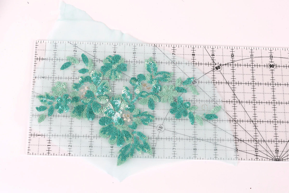 a clear ruler with a floral pattern of green sequins and leaves on it.