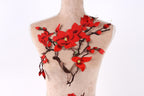A mannequin torso with red flowers and branches attached to it, creating a decorative and artistic design.