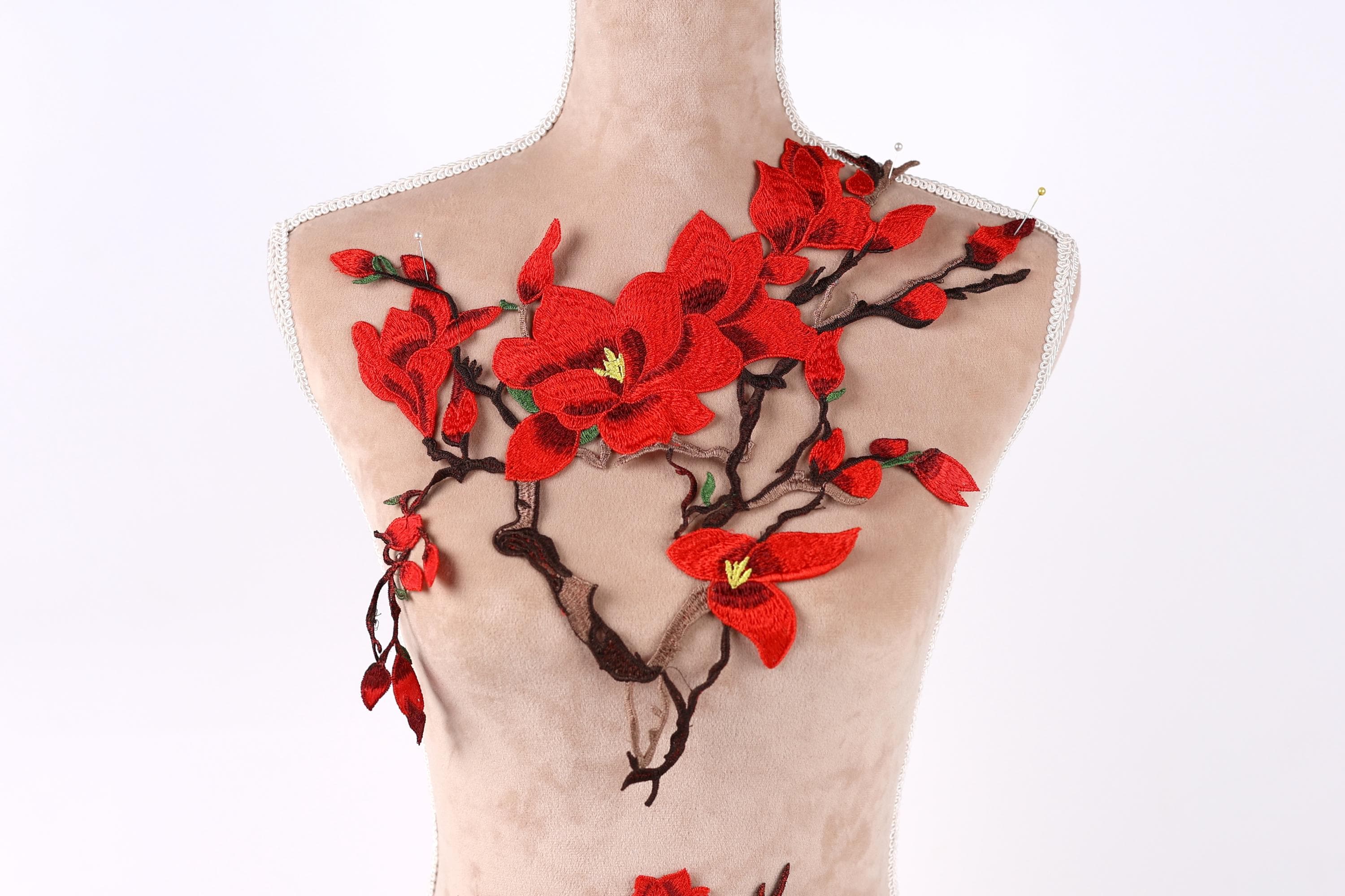 A mannequin torso with red flowers and branches attached to it, creating a decorative and artistic design.
