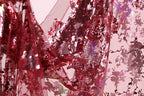 a close-up view of a fabric with a red and purple floral pattern, with a shiny, sequined texture.