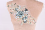 a mannequin torso with a decorative floral embroidery on it. The embroidery features a variety of flowers and leaves in shades of blue and white, creating a visually appealing and intricate design.