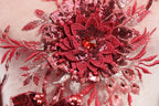 a close-up view of a red and pink floral embroidered piece, with intricate details and embellishments such as sequins and beads.