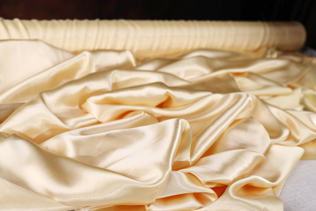 a close-up view of a pile of crumpled, light yellow satin fabric.