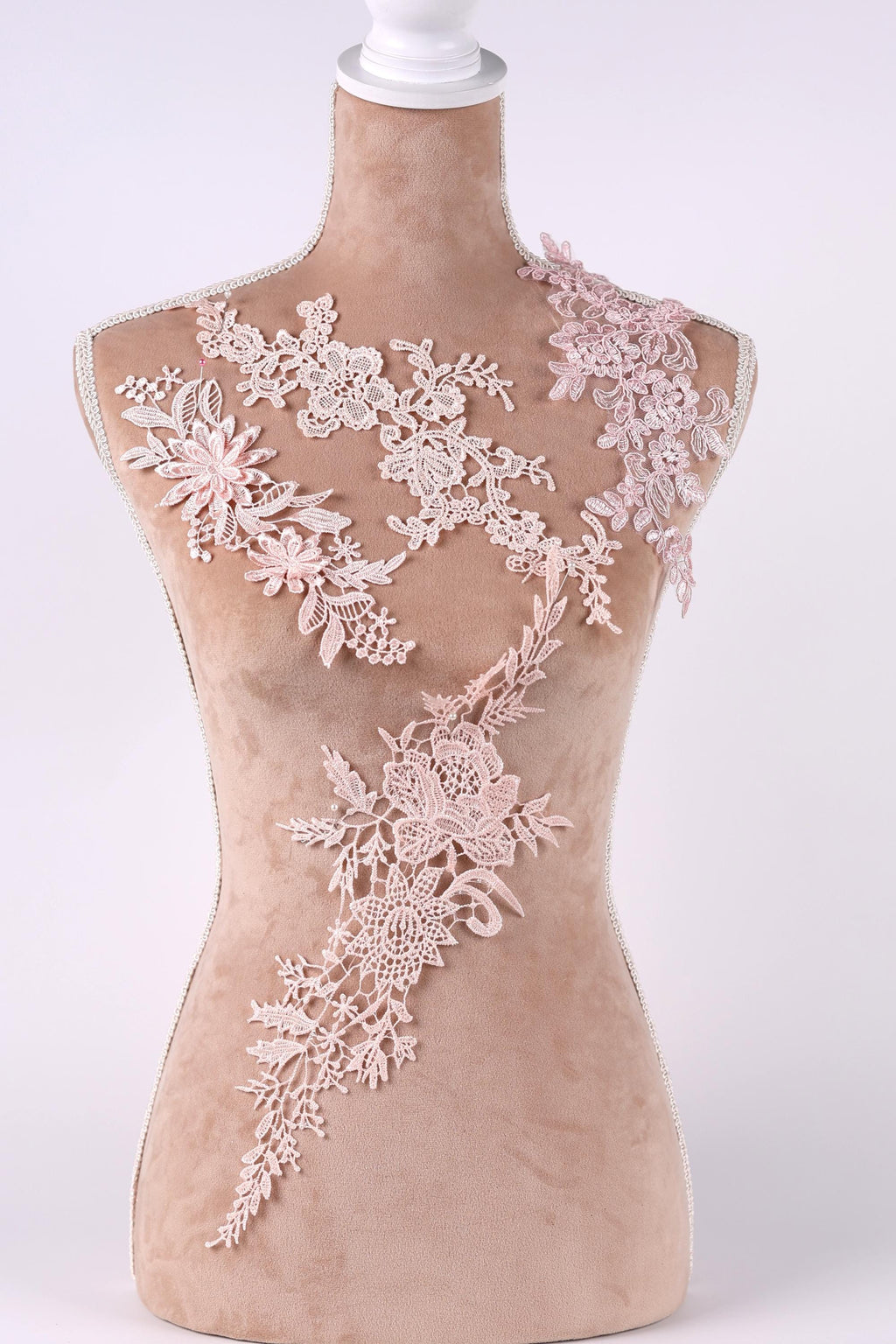 A mannequin wearing a dress with delicate pink floral lace appliques on the shoulders and back.