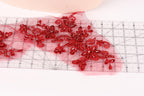 a close-up view of a red floral pattern on a transparent surface, with a ruler visible in the background.