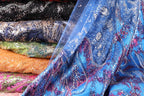 A close-up view of a stack of colorful, patterned fabric pieces, with a focus on the intricate designs and textures of the materials.
