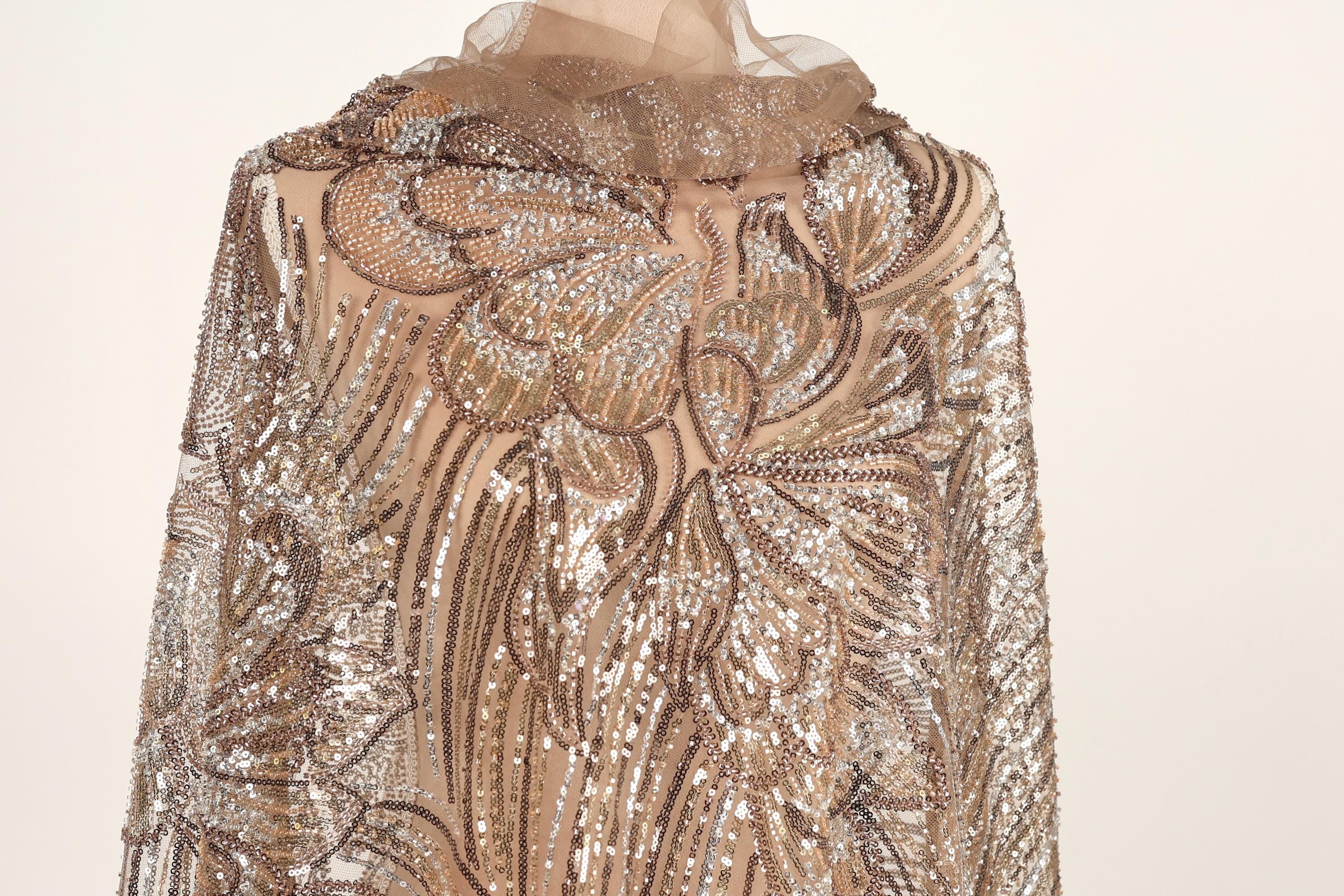 a close-up view of a gold and beige sequined dress with a floral pattern.