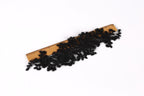 a wooden ruler with black lace or fabric attached to it, placed on a white background.