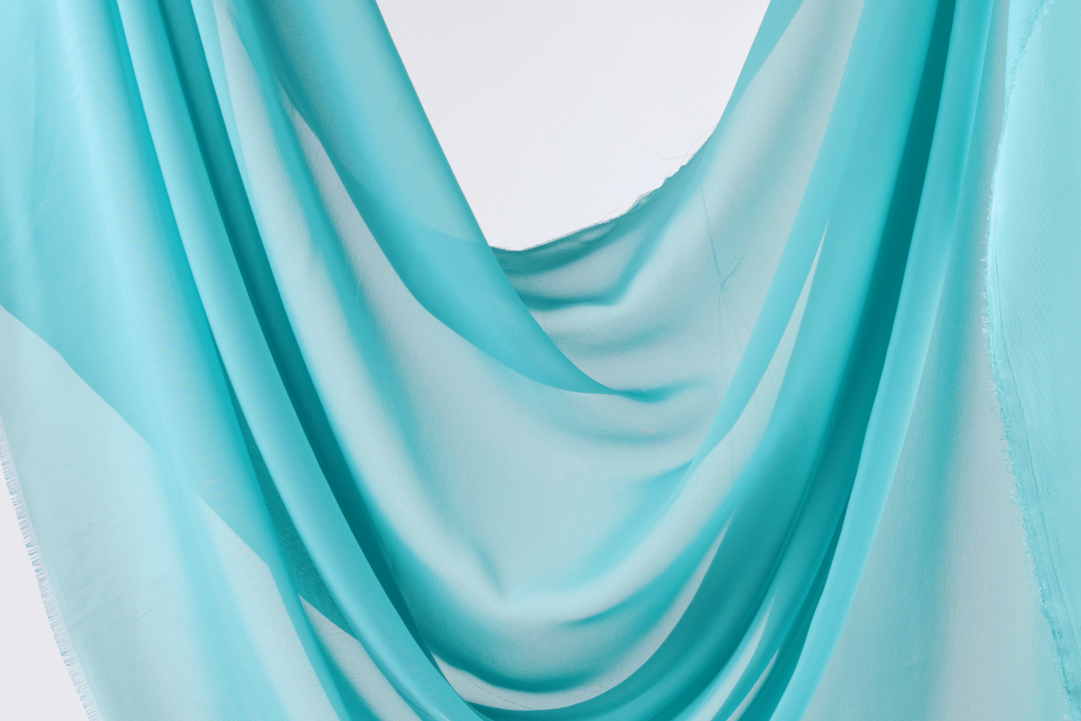 A close-up view of a light blue fabric, possibly a sheer or chiffon, with a soft, flowing texture.