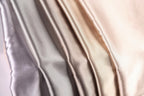 A close-up image of a fabric with a gradient of colors, transitioning from a light gray to a darker gray to a beige.