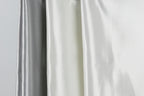 three different colored silks hanging side by side, with the middle one being white and the two on either side being silver.