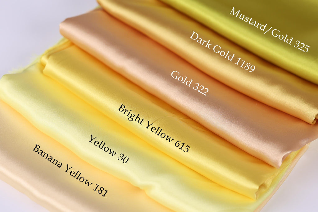 A stack of six fabric swatches in various shades of yellow, including mustard, gold, bright yellow, banana yellow, and bright yellow.