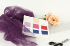 various fabric swatches, a pair of scissors, and a rose, all arranged on a white background.