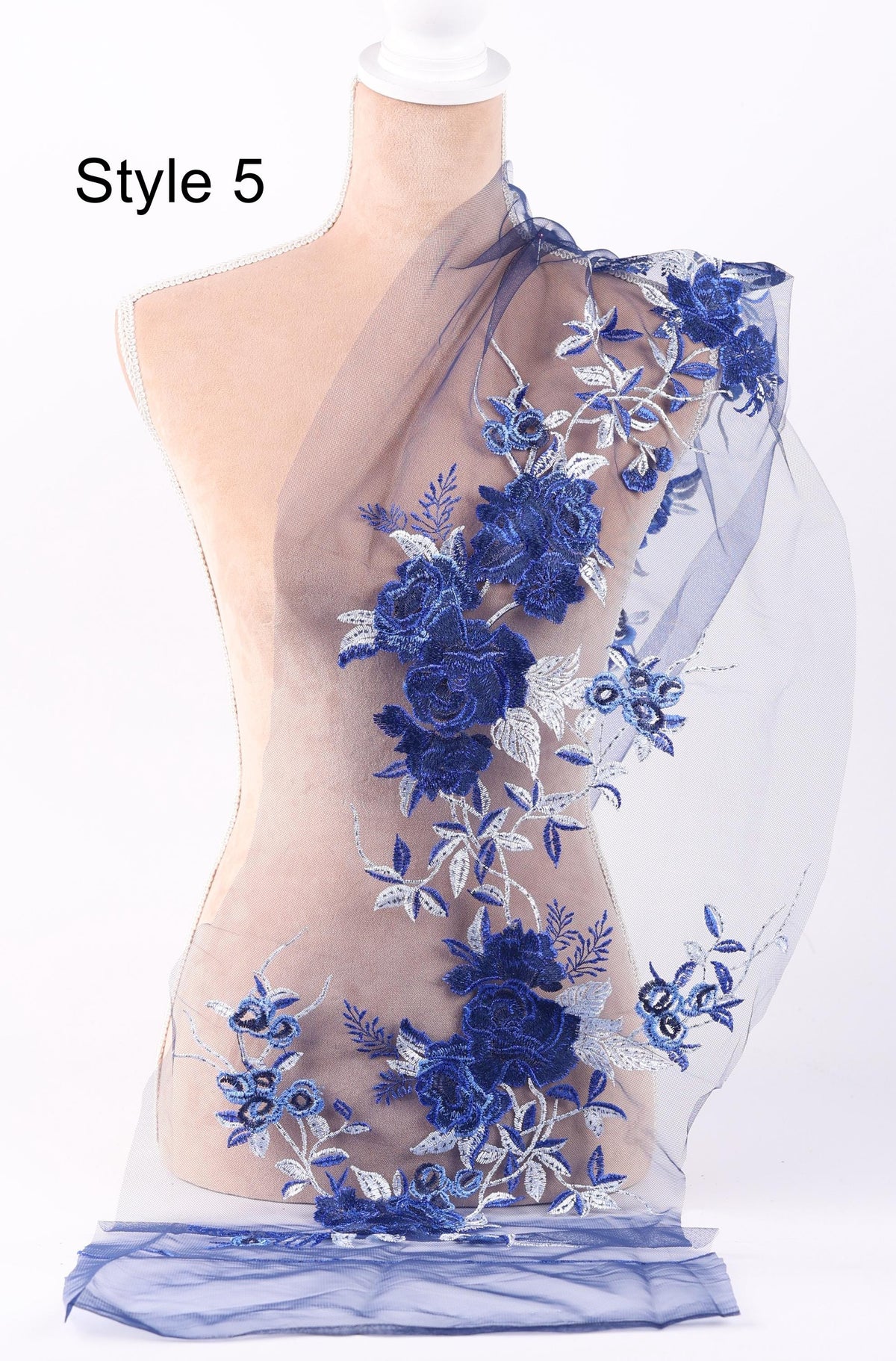 A mannequin wearing a dress with a blue floral pattern on the shoulder and a sheer blue fabric draped over the shoulders.