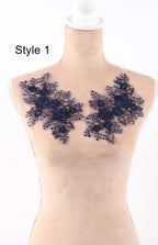 A mannequin wearing a beige dress with blue floral lace appliques on the chest area.