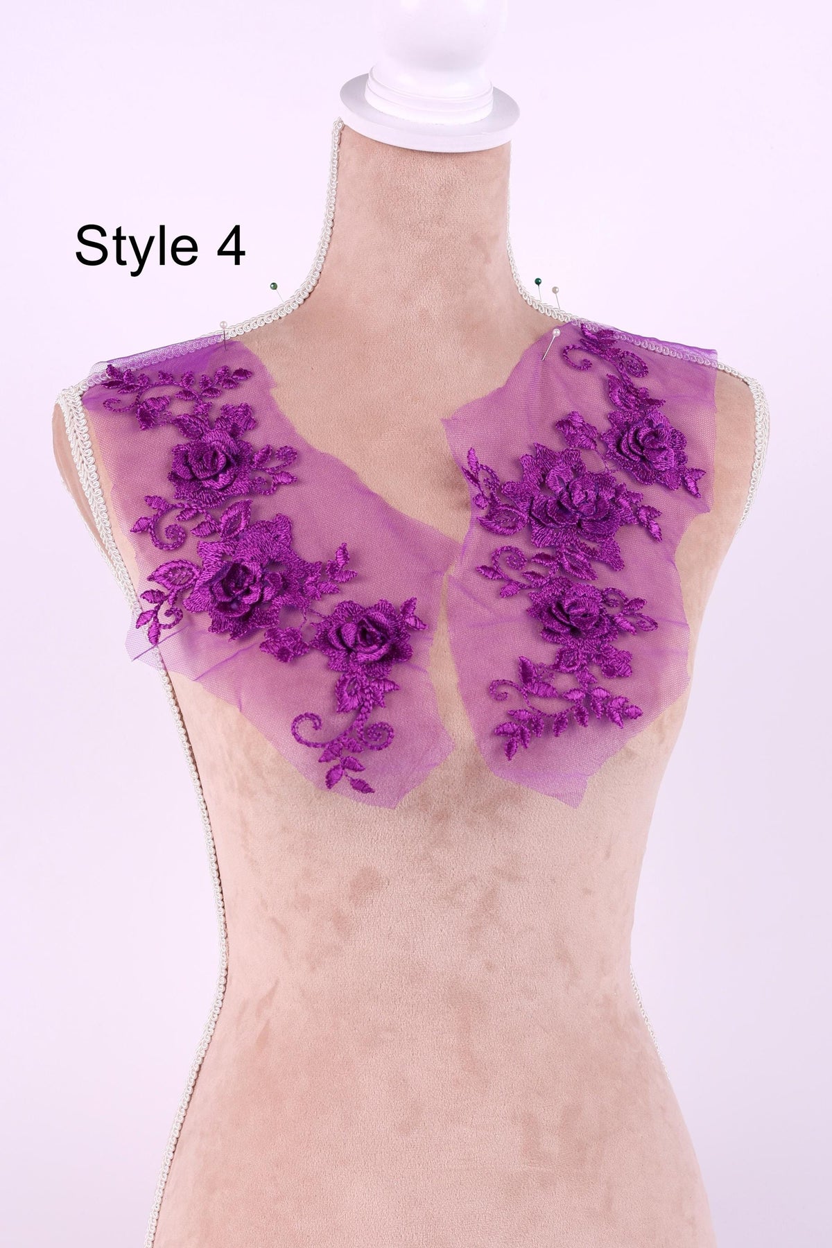 A mannequin wearing a dress with purple floral embroidery on the shoulders.