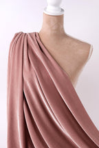 A mannequin wearing a pink velvet fabric draped over its shoulder.
