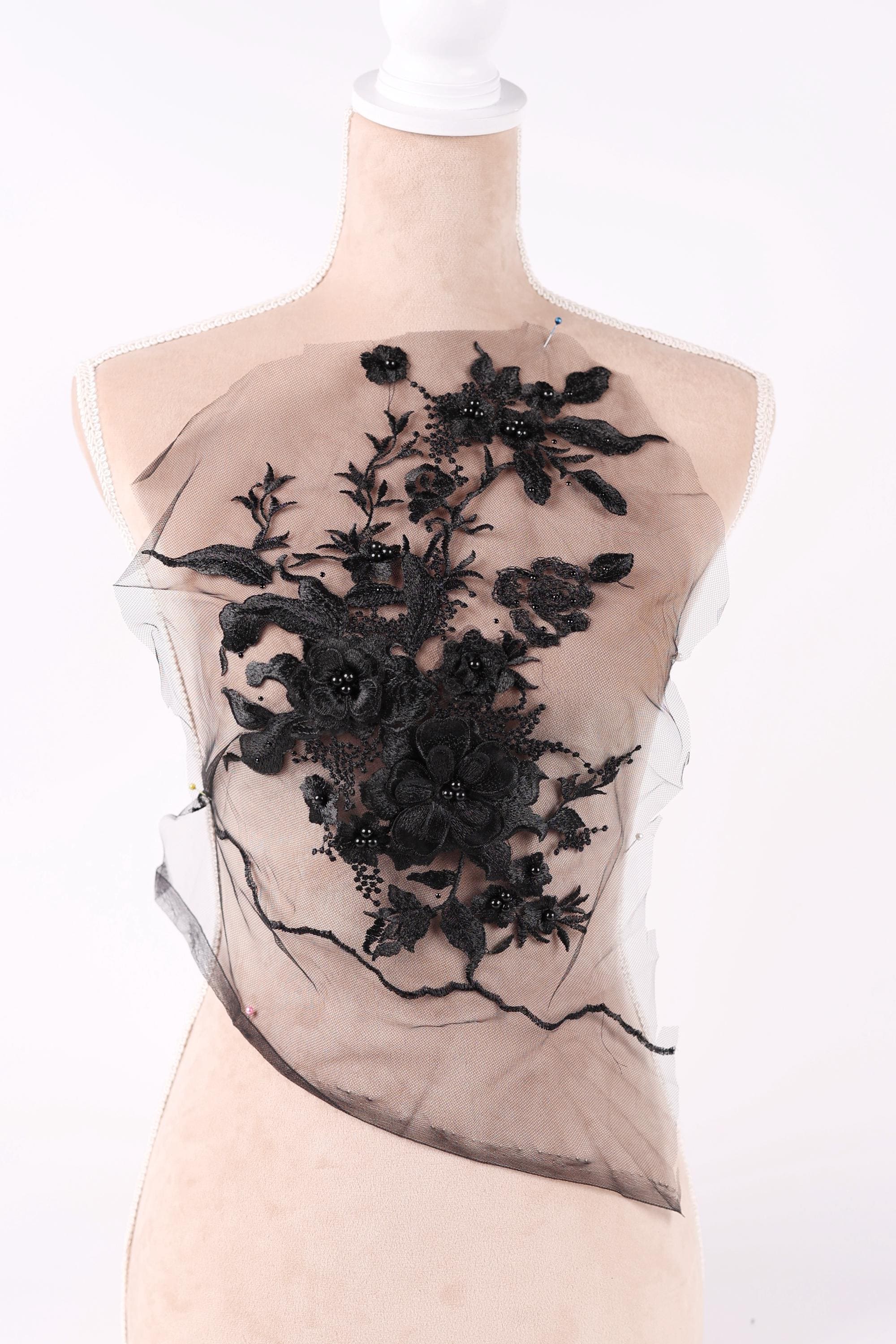 A mannequin wearing a dress with a black floral embroidered on the front.