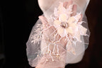 A hand holding a delicate, intricately designed flower made of lace and pearls against a dark background.
