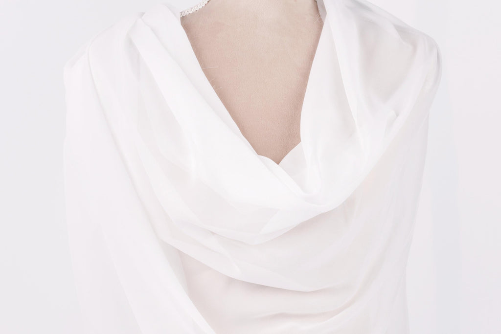 A close-up view of a white fabric draped over a person's body, with a soft, flowing appearance.