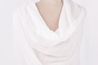 A close-up view of a white fabric draped over a person's body, with a soft, flowing appearance.
