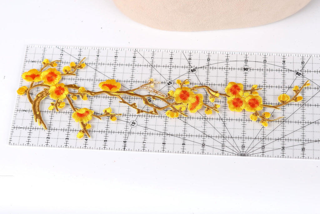a clear ruler with a floral design on it, including yellow and orange flowers and branches.