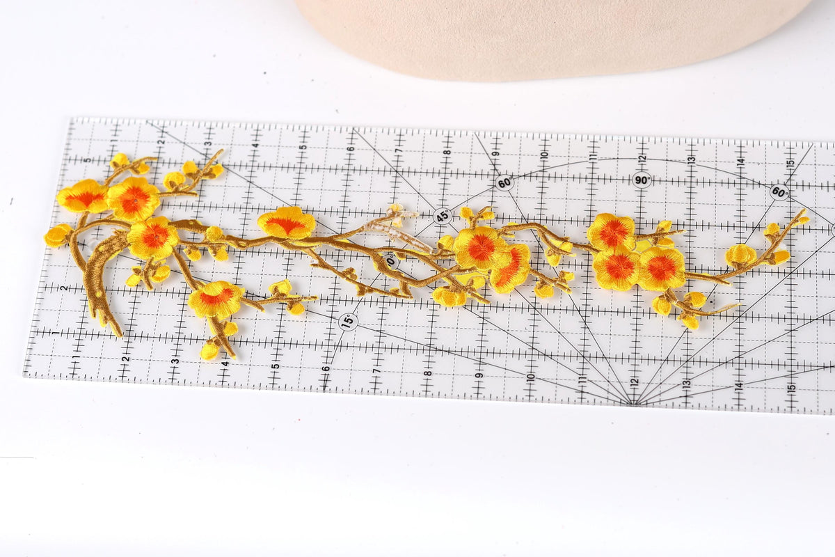 a clear ruler with a floral design on it, including yellow and orange flowers and branches.