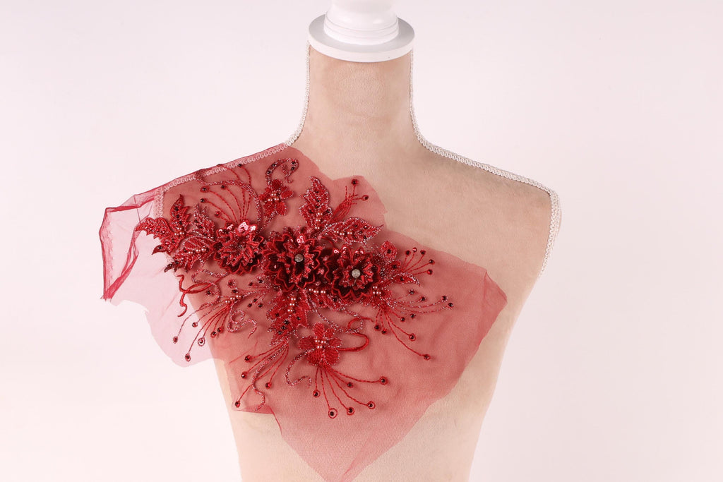 A mannequin wearing a red, sheer fabric with a floral pattern and sequin embellishments.