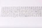 a piece of white lace with a floral pattern, placed on a transparent ruler.