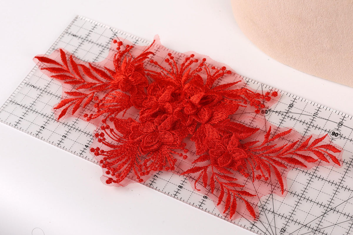 a close-up view of a red floral lace piece, with its intricate details and vibrant color. The lace appears to be a decorative element, possibly used for sewing or crafting purposes.