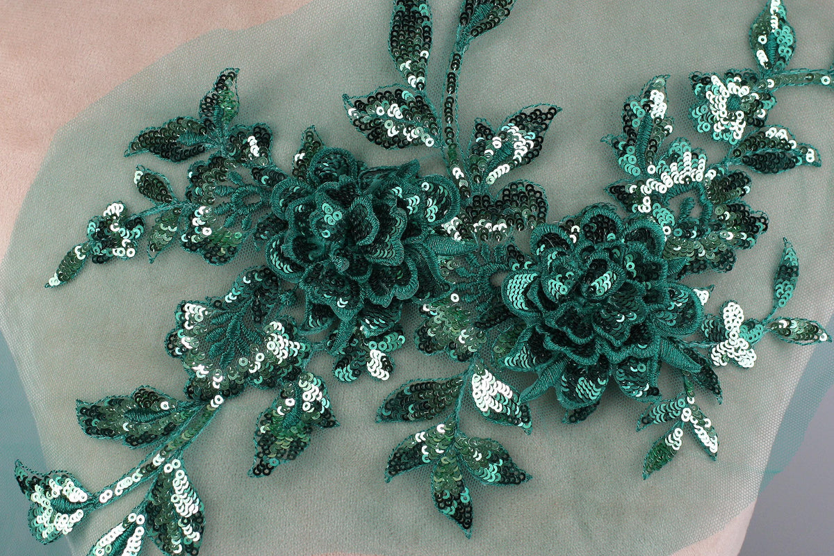 a close-up view of a delicate, intricate floral embroidery with a green and white color scheme. The embroidery is composed of numerous small sequin flowers and leaves, creating a visually striking and detailed design.